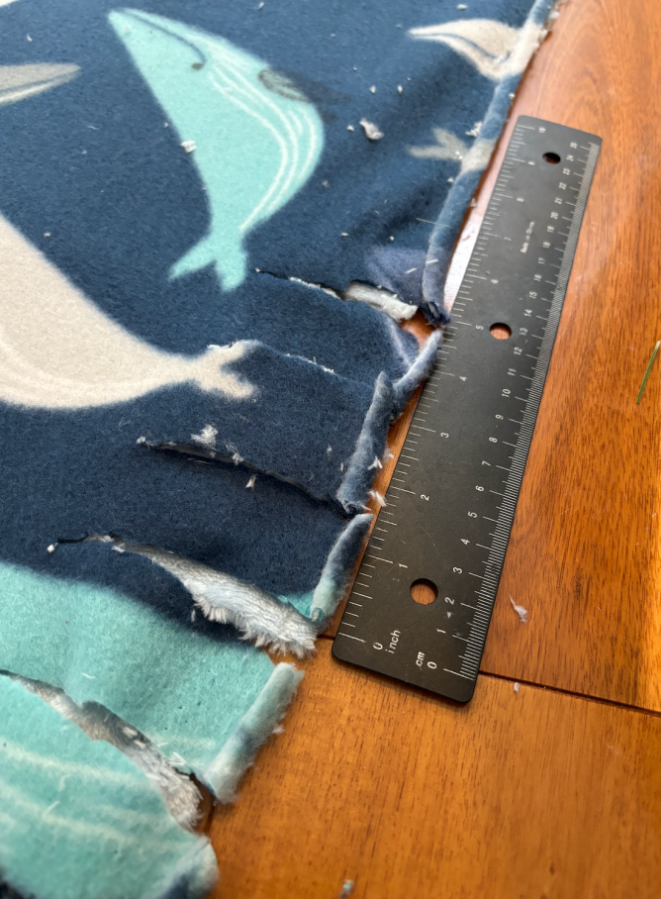 Measured out cuts on the edge of the blanket, next to a ruler